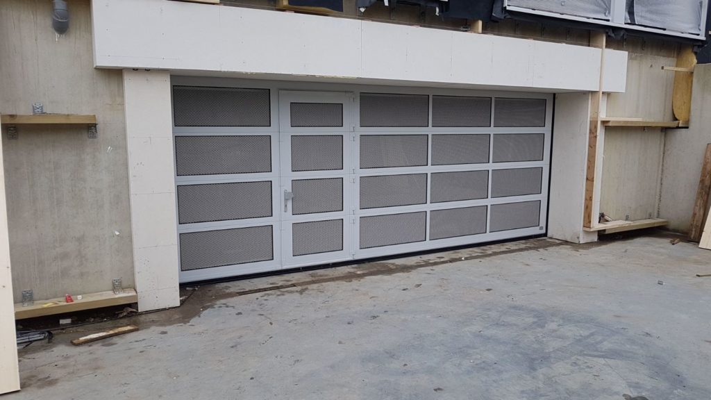 parkeergaragedur met strekmetaal en een loopdeur gemonteerd door Ton Smit deuren